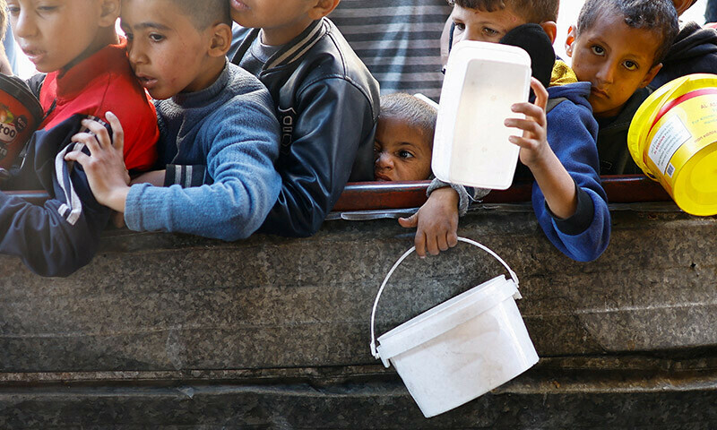 Palestinians wait to receive food cooked by a charity kitchen amid shortages of food supplies in Rafah in the southern Gaza Strip on January 16. &mdash; Reuters