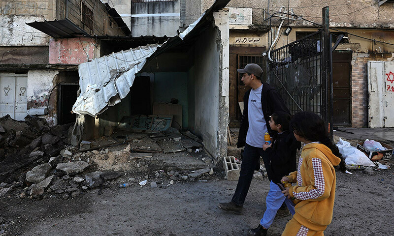 Palestinian people walk past a damaged building in a refugee camp in Tulkarem, where the Israeli army carried out overnight raids, on January 19, 2024 in the occupied West Bank. &mdash; AFP