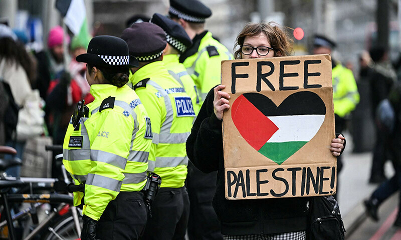 A pro-Palestinian supporter holds a placards as she walks past Met police officers while taking part in a &ldquo;Day of Action for Palestine&rdquo; demonstration outside the British multinational arms, security and aerospace company BAE Systems, in London, on January. &mdash; AFP