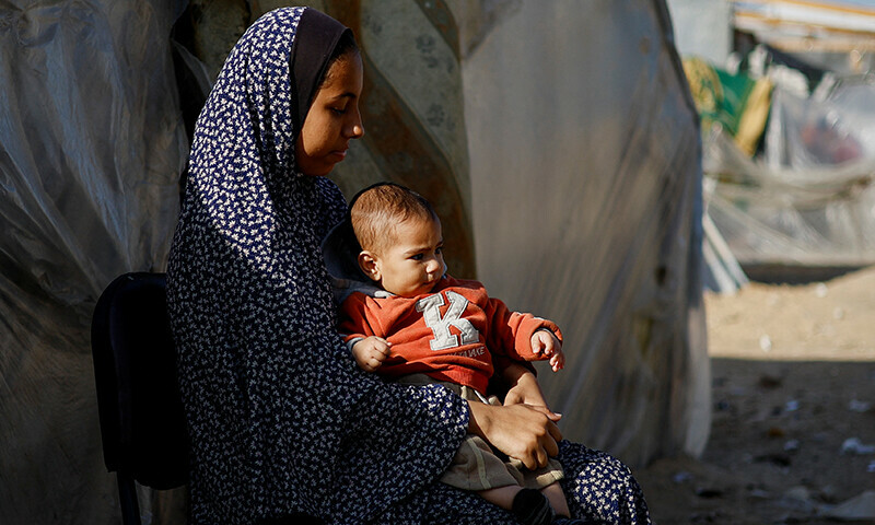 A displaced Palestinian woman and child, who fled their house due to Israeli strikes, sit in a tent camp, amid the ongoing Israeli bombardment in Rafah in the southern Gaza Strip on January 22.&mdash; Reuters