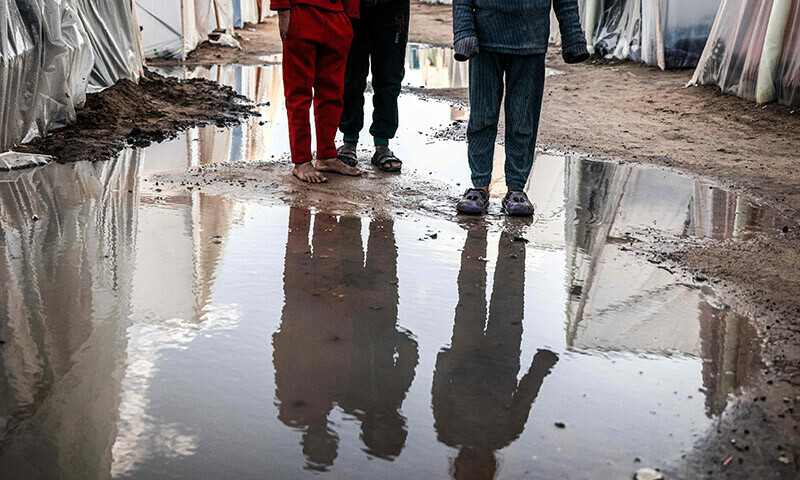 Displaced Palestinian children stand amid tents flooded by heavy rain at a makeshift camp in Rafah in the southern Gaza Strip on January 27. &mdash; AFP