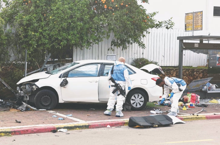 ISRAEL’s forensic officials inspect a damaged car following the ramming attack in Raanana, on Monday.—AFP
