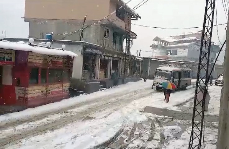 A passenger coach passes through a snow-clad road in the town of Sharda, located some 137 kilometres northeast of Muzaffarabad in the upper belt of Neelum valley on Monday. — Dawn