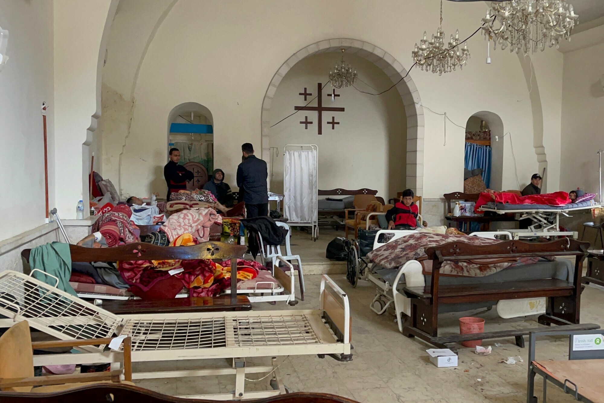 A priest stands next to a patient and his relatives on February 20 in the main hall of Gaza City&rsquo;s Baptist church, also known as the Maamadani church, which was turned into an extension space for rehabilitation affiliated with the nearby Al-Ahli Arab Hospital to cope with the numbers of patients. &mdash; AFP