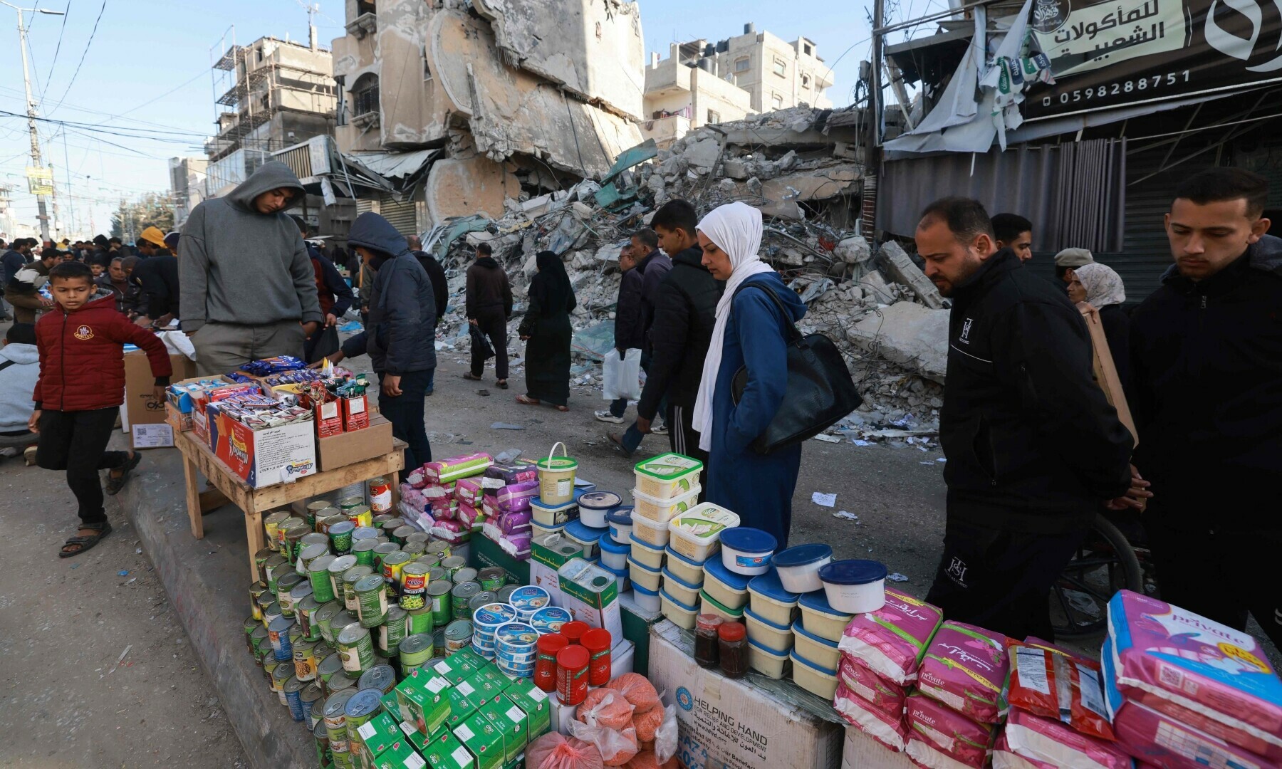  Palestinians walk past stalls set up in a street in Rafah, in the southern Gaza Strip on March 10, 2024. &mdash; AFP 