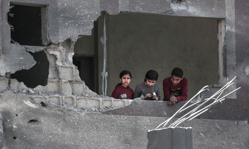  Palestinian youths look out a window in a damaged building following overnight Israeli bombardment which hit the al-Habash family home at the Nuseirat refugee camp in the central Gaza Strip on March 20, 2024. &mdash; AFP 