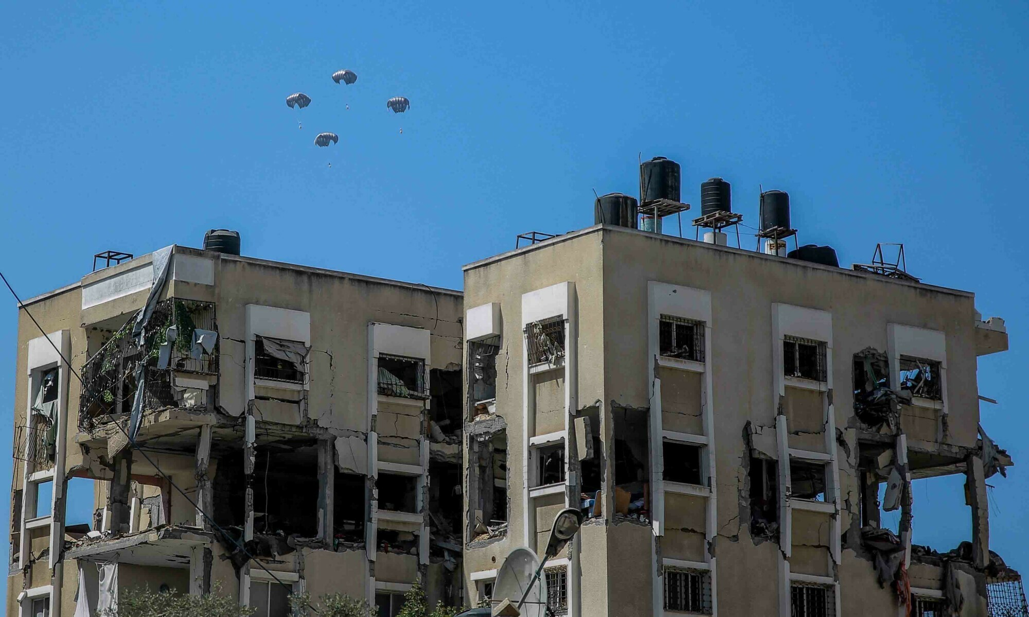 Humanitarian aid parcels attached to parachutes are airdropped from a military aircraft over the Gaza Strip on March 21. — AFP