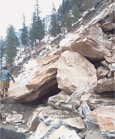 A man walks through a landslide affected portion of main Neelum Valley Road in Shaikh Bela village, some 152km from Muzaffarabad on Sunday. &mdash; Dawn