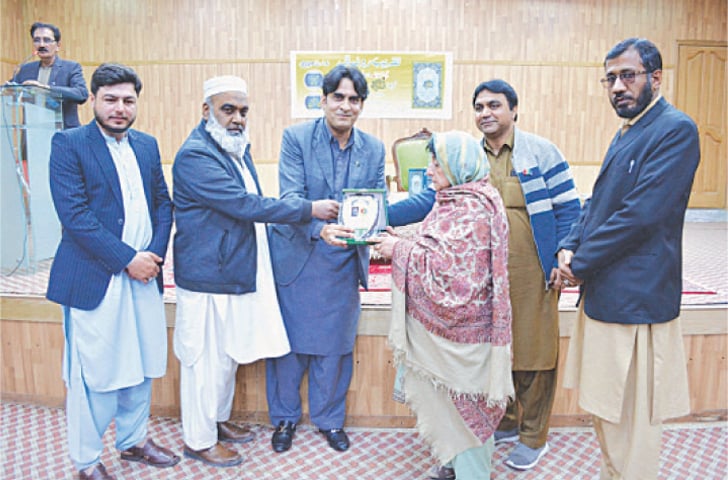 WRITER Qudsia Qudsee being presented a souvenir in Peshawar on Sunday at the launching ceremoney of her book. — Dawn