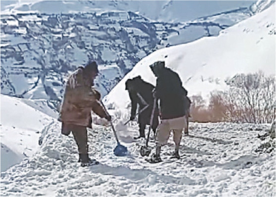 The people of Melp village in Torkhow valley of Upper Chitral clear the road with shovels. — Dawn