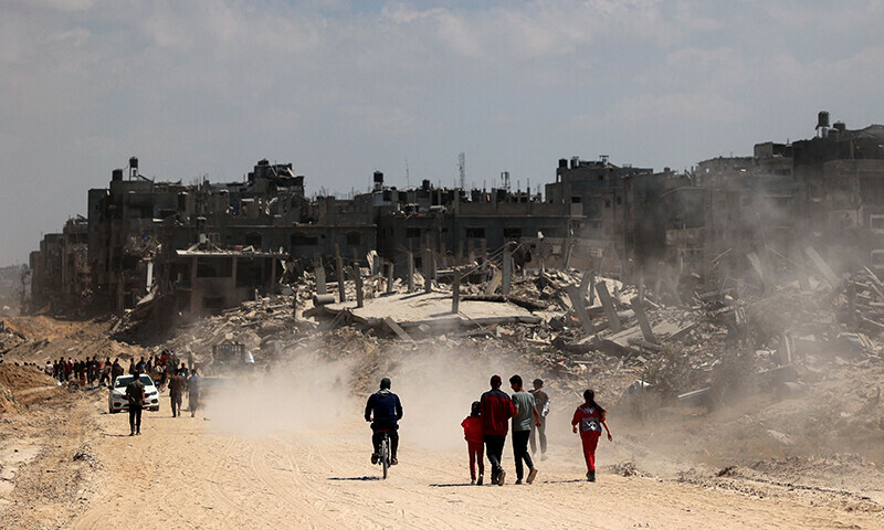 Palestinians use a road lined with damaged and destroyed buildings in Khan Younis on April 7 after Israel pulled troops out of the southern Gaza Strip. &mdash; AFP