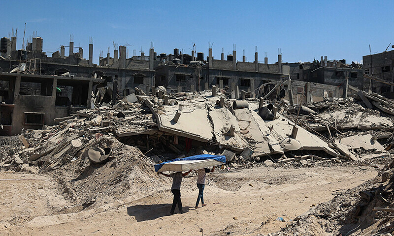 Palestinians carry a mattress on a path amid building rubble in Khan Younis on April 7 after Israel pulled troops out of the southern Gaza Strip. &mdash; AFP