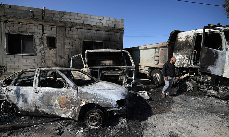 A Palestinian inspects the damage to vehicles in the village of Mughayir in the Israeli-occupied West Bank on April 13, 2024. &mdash; AFP