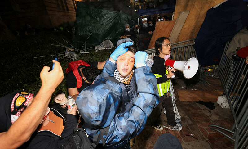 Pro-Palestinian protesters help one another by rinsing their eyes at their encampment on the University of California, Los Angeles (UCLA) campus, on May 1. &mdash; REUTERS