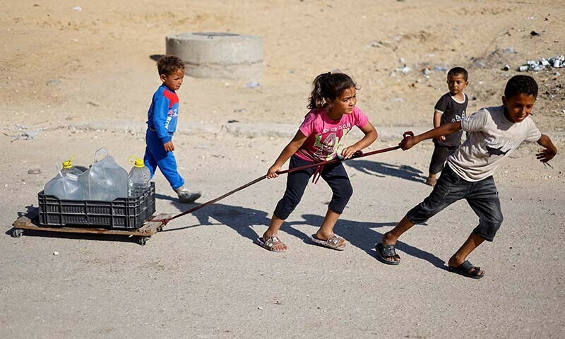 Palestinian children pull water containers as people flee Rafah amidst an Israeli ground and air operation in the southern Gaza city on May 9. &mdash; Reuters