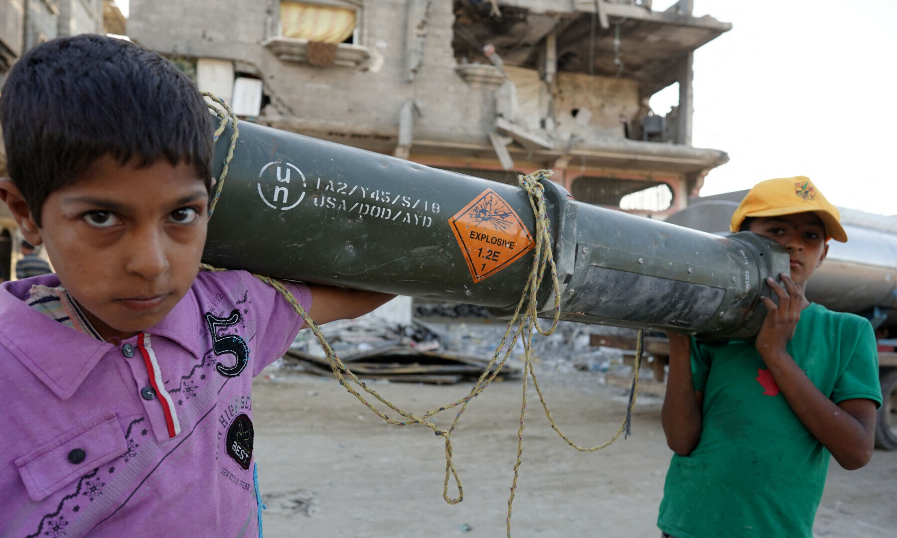  Palestinian children carry an empty US ammunition container in Khan Younis in the southern Gaza Strip on May 16. &mdash; AFP 