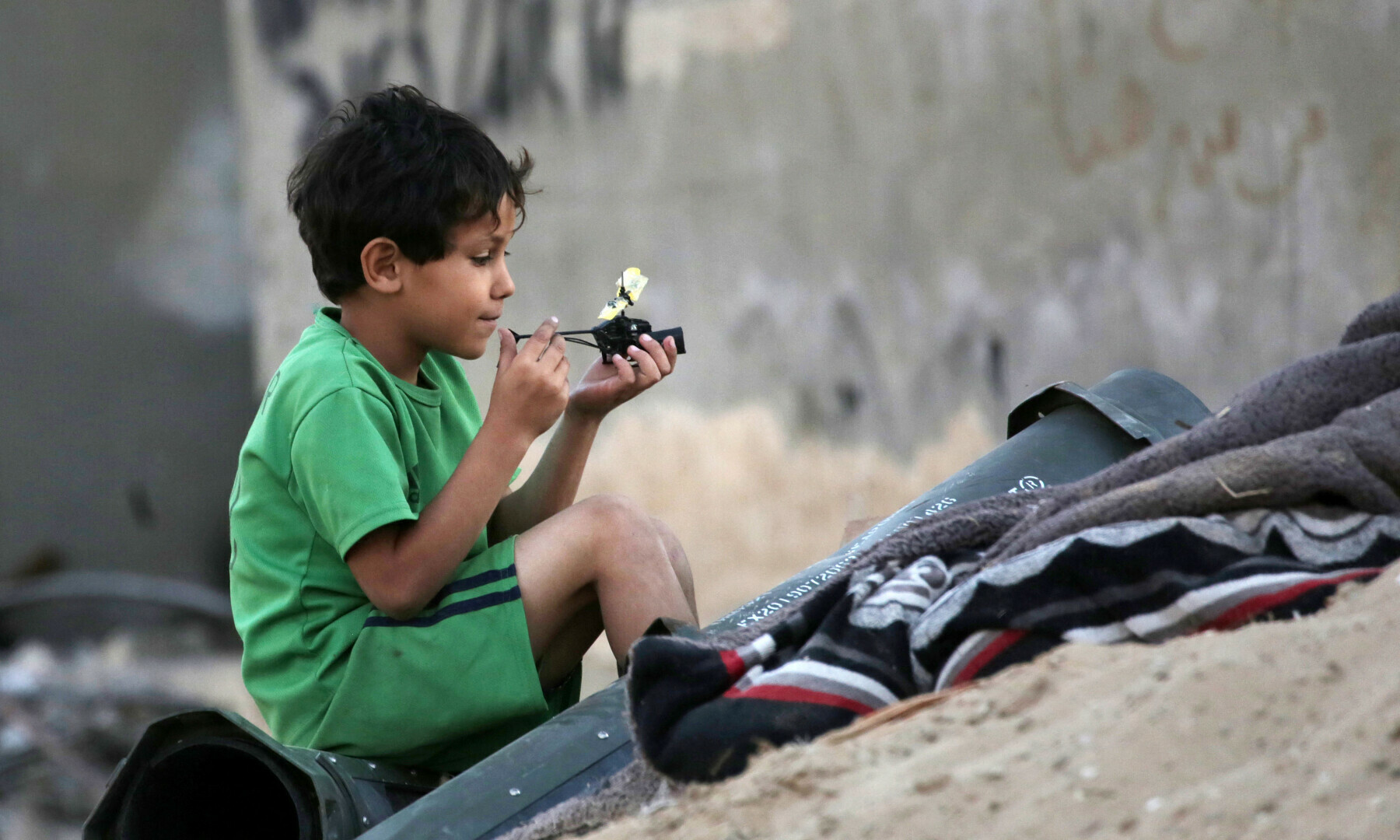  A Palestinian child plays next to empty ammunition containers in Khan Younis in the southern Gaza Strip on May 16. &mdash; AFP 