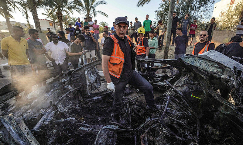Palestinians check a burnt vehicle following an Israeli strike in the central Gaza Strip on May 31. &mdash; AFP