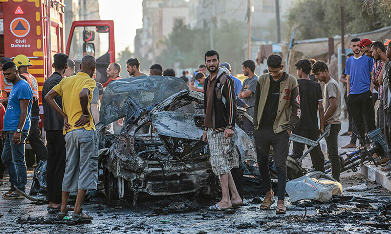 Palestinians check a burnt vehicle following an Israeli strike in the central Gaza Strip on May 31. &mdash; AFP