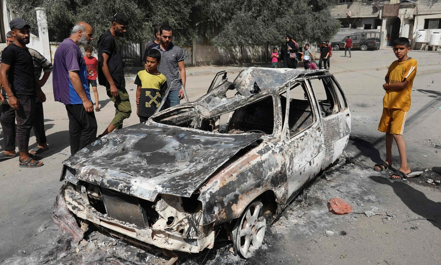  Palestinians inspect a burnt car following an operation by the Israeli Special Forces in the Nuseirat camp, in the central Gaza Strip on June 8, 2024. &mdash; AFP 