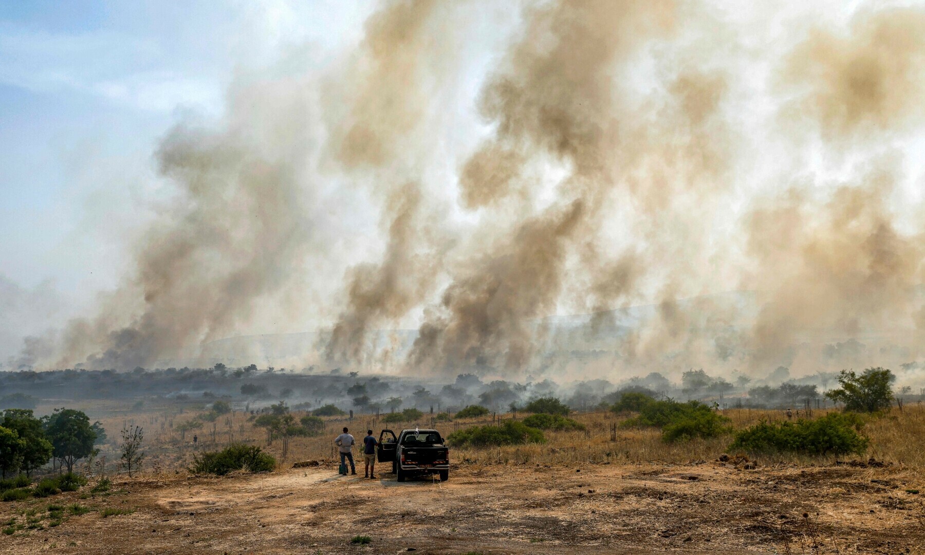  Two men stand by a truck as they watch smoke plumes rising from a fire in a field after rockets launched from southern Lebanon landed near the outskirts of Katzrin in the Israel-annexed Golan Heights on June 13, 2024. &mdash; AFP 