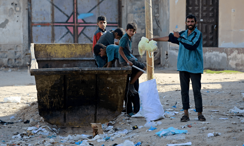 Palestinians look through a dumpster in Deir al-Balah, in central Gaza Strip on June 13, 2024. &mdash; AFP