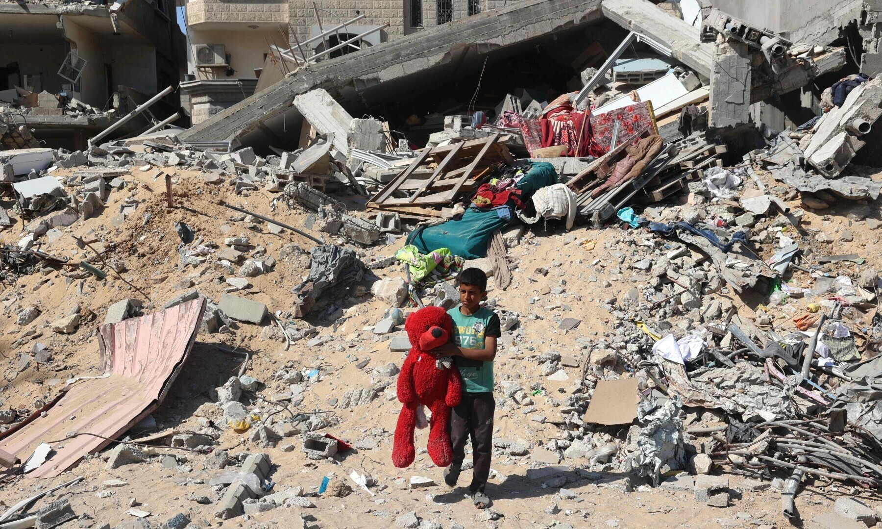  A Palestinian child walks with a stuffed bear recovered from the rubble of a destroyed building following Israeli bombardment in Khan Younis on June 21, 2024. &mdash; AFP 