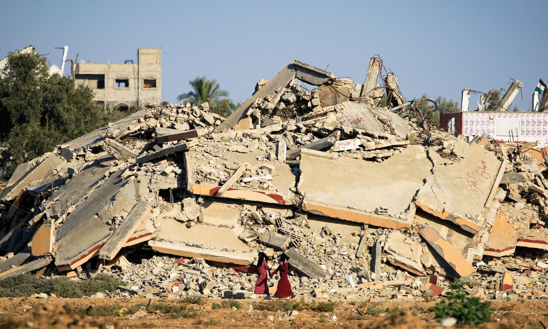  Palestinian women walk past a building that was destroyed during Israeli bombardment at al-Bureij refugee camp in the central Gaza Strip on June 24, 2024. &mdash; AFP 