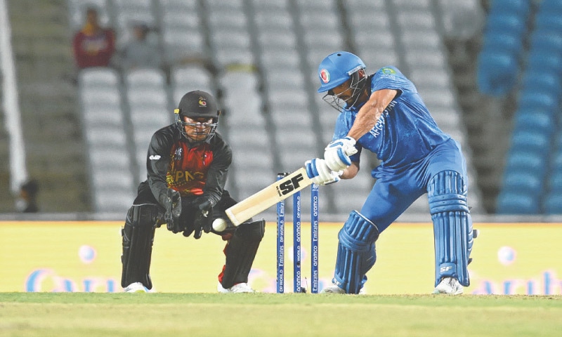TAROUBA: Afghanistan’s Gulbadin Naib plays a shot as Papua New Guinea wicket-keeper Kiplin Doriga looks on during their Group C match at the Brian Lara Cricket Academy Stadium.—AFP