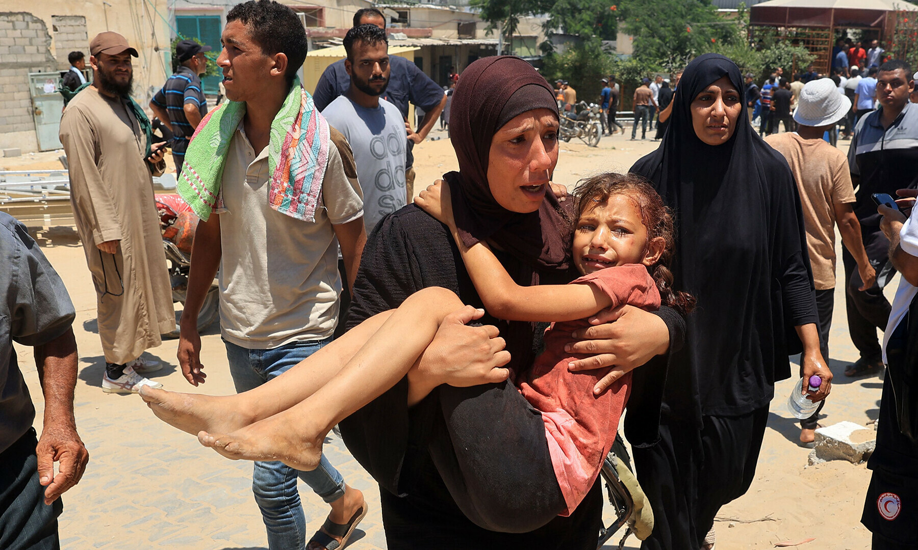 A Palestinian woman carries an injured child to the Nasser hospital in Khan Younis on July 13, 2024.&mdash;AFP