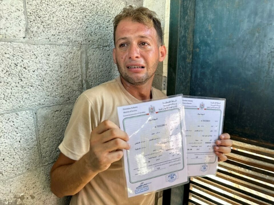 Mohammed Abu Al-Qumsan, whose wife Jumann, and newborn twins Asser and Ayssel were killed in an Israeli strike while he was bringing the twins&rsquo; birth certificates, according to medics, reacts as he holds the certificates, in Deir Al-Balah in the central Gaza Strip, August 13. &mdash; Reuters