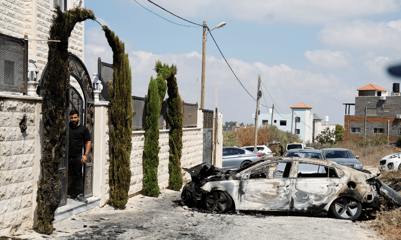 A Palestinian man stands near a vehicle destroyed during an Israeli settlers’ attack in the village of Jeit, near Qalqilya in Israel-occupied West Bank, on Aug 16, 2024. — Reuters