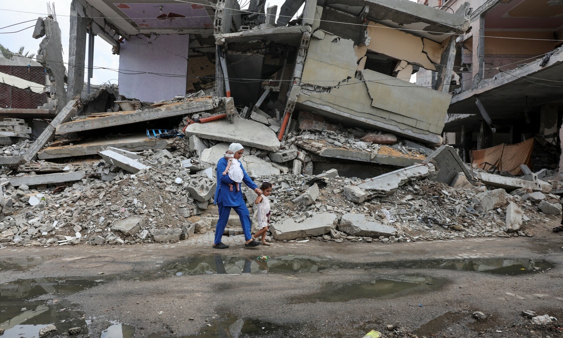  A displaced Palestinian mother, Wafaa Abdelhadi, walks past the rubble of a house destroyed in an Israeli strike as she returns to her shelter with her daughters Lynn and Roueida, after they got vaccinated against polio, in Deir Al-Balah, central Gaza Strip on Sept 1, 2024. &mdash; Reuters/Ramadan Abed 