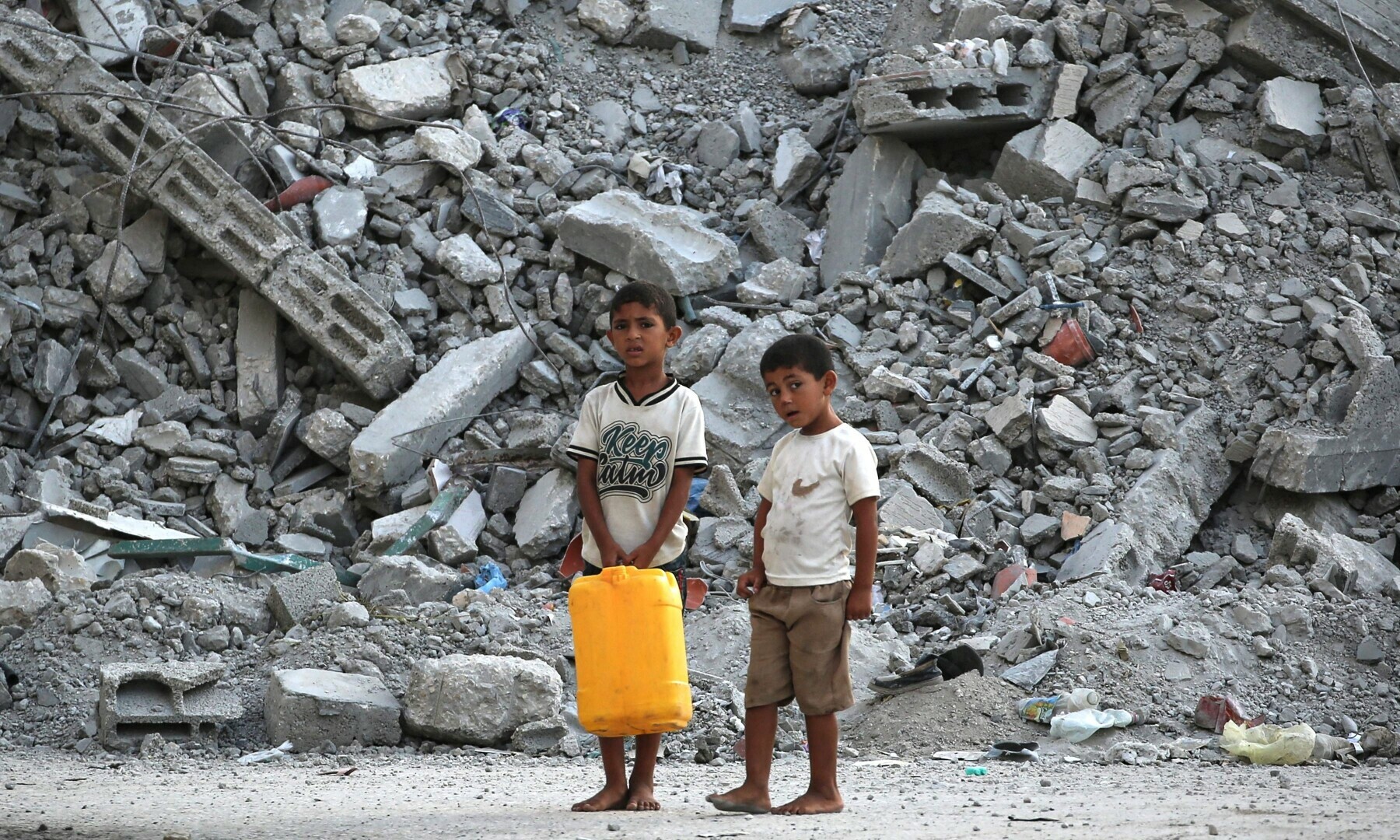 Palestinian boys stand with a water container near a pile of debris in Nuseirat in the central Gaza Strip, on Sept 13, 2024. — AFP