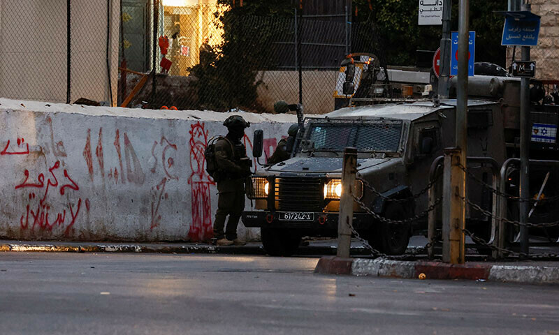 A soldier of the Israeli army stands next to a military vehicle in a street near the building where the Al Jazeera office is located, in Ramallah, in the Israeli-occupied West Bank on September. &mdash; Reuters