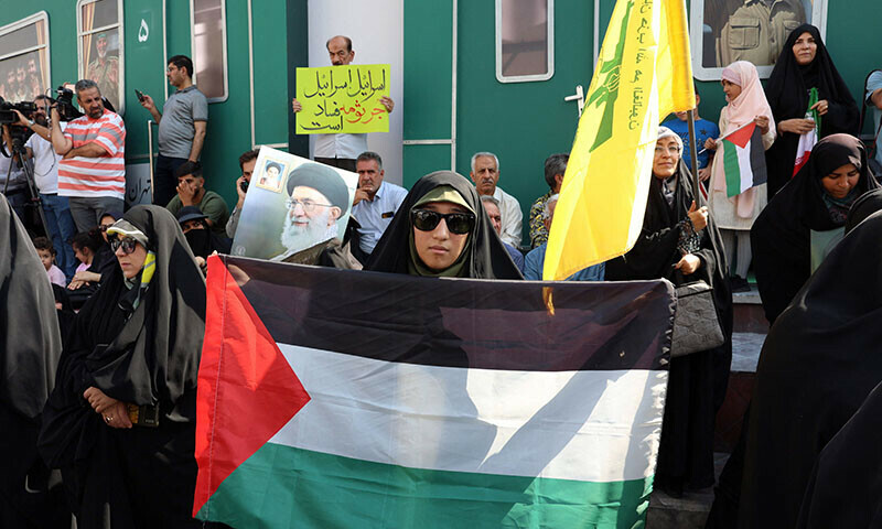 A woman deploys a Palestinian flag as another waves the flag of Lebanon&rsquo;s Hezbollah movement during an anti-Israel protest in Tehran on September 27. &mdash; AFP