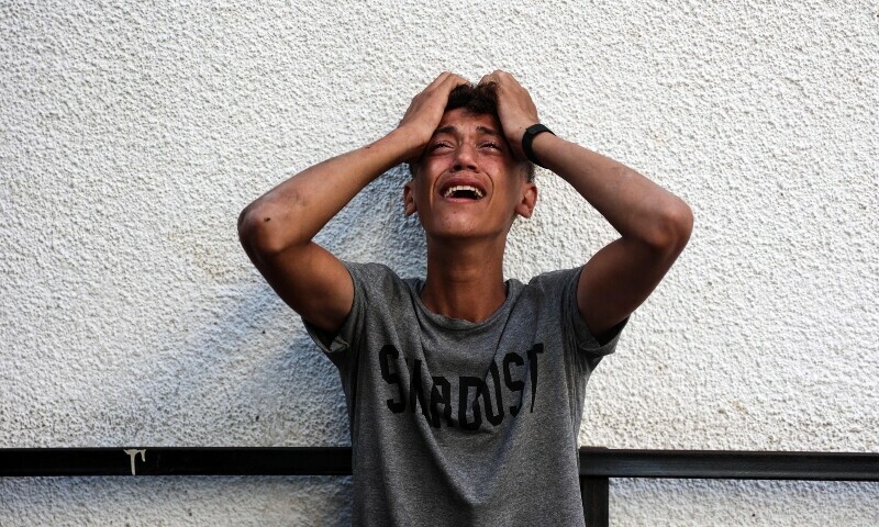 A Palestinian youth reacts upon seeing the bodies of relatives killed in an overnight Israeli airstrike in the Jabalia refugee camp in the northern Gaza Strip, in front of the al-Maamadani on October 12. &mdash; AFP
