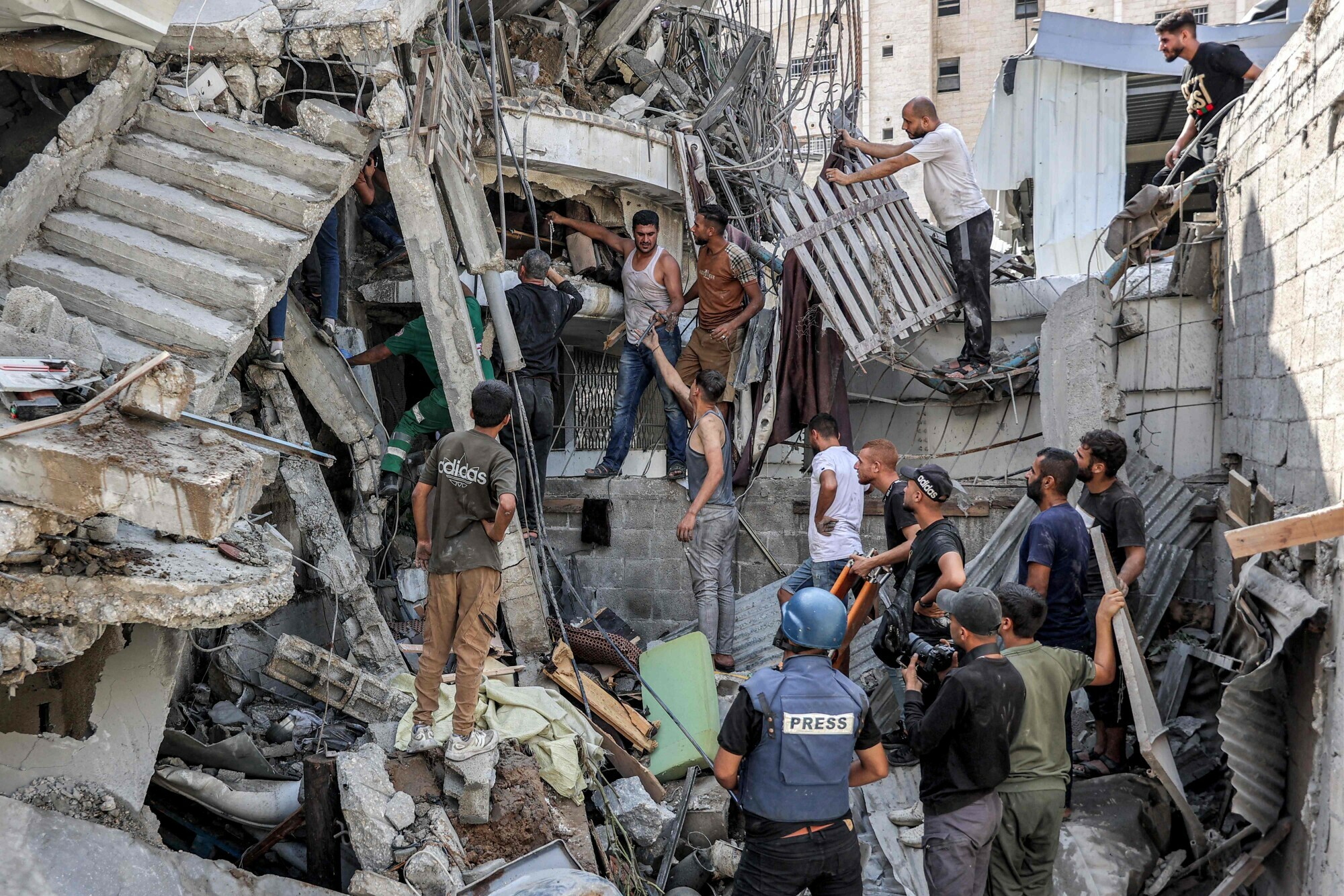 People gather outside a collapsed building as they attempt to extricate a man from underneath the rubble following Israeli bombardment in the Saftawi district in Jabalia in the northern Gaza Strip on October 15. &mdash; AFP