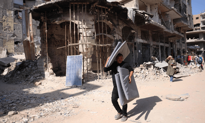  Palestinians walk past damaged buildings in Khan Younis in the southern Gaza Strip on Oct 29, 2024. — AFP 