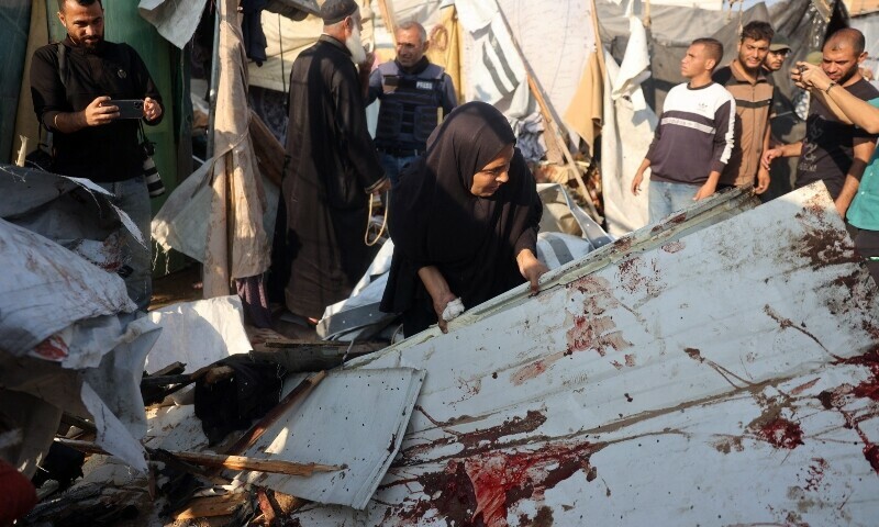 A woman lifts a blood-stained board as displaced Palestinians check the damage following an Israeli strike that hit tents set up in the vicinity of the Al-Aqsa Martyrs hospital in Deir el-Balah in the central Gaza Strip on November 9. &mdash; AFP