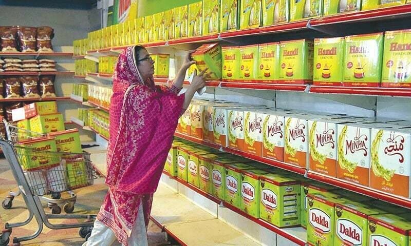 A woman lifts a box of ghee from a supermarket. &mdash; Dawn/File