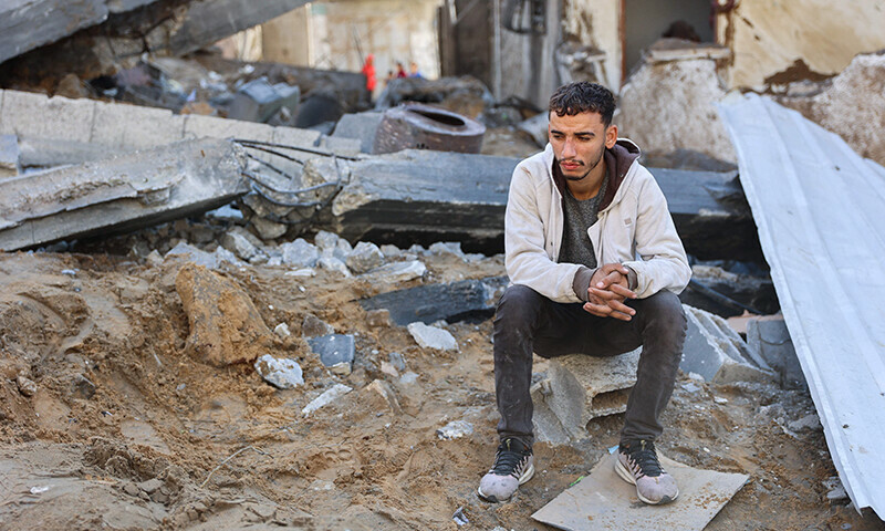 A man reacts as he sits on the rubble of a house destroyed in an Israeli strike as rescuers search for casualties on al-Jalaa street in central Gaza City on November 18. &mdash; AFP