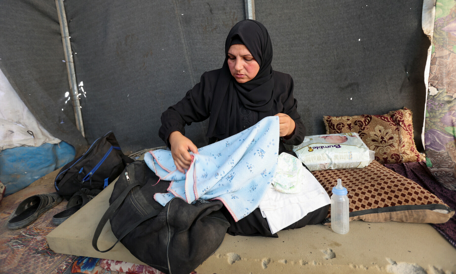  Noura, the mother of Palestinian infant Jumaa Al-Batran, who died of hypothermia after living in a tent with his displaced family, shows his belongings at their tent, in Deir Al-Balah in the central Gaza Strip on Dec 29, 2024. &mdash; Reuters/Ramadan Abed 
