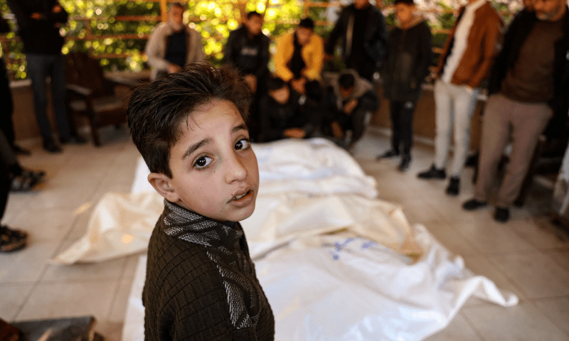 A child stands beside the bodies of four members of the Palestinian al-Qadra family (parents and their two children) killed in an Israeli strike that hit their tent north of Khan Younis in the southern Gaza Strip, in the yard of the Nasser hospital on Jan 18, 2025. — AFP