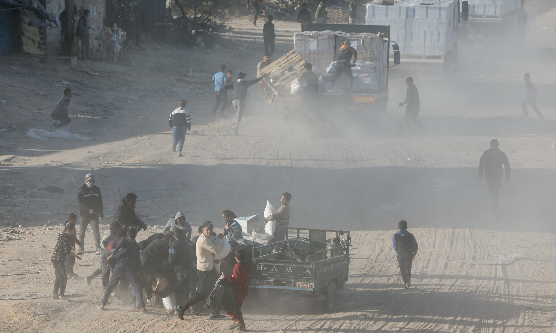  Palestinians rush to take aid from moving trucks entering Rafah, in the southern Gaza Strip on January 20. &mdash; Reuters/Mohammed Salem 