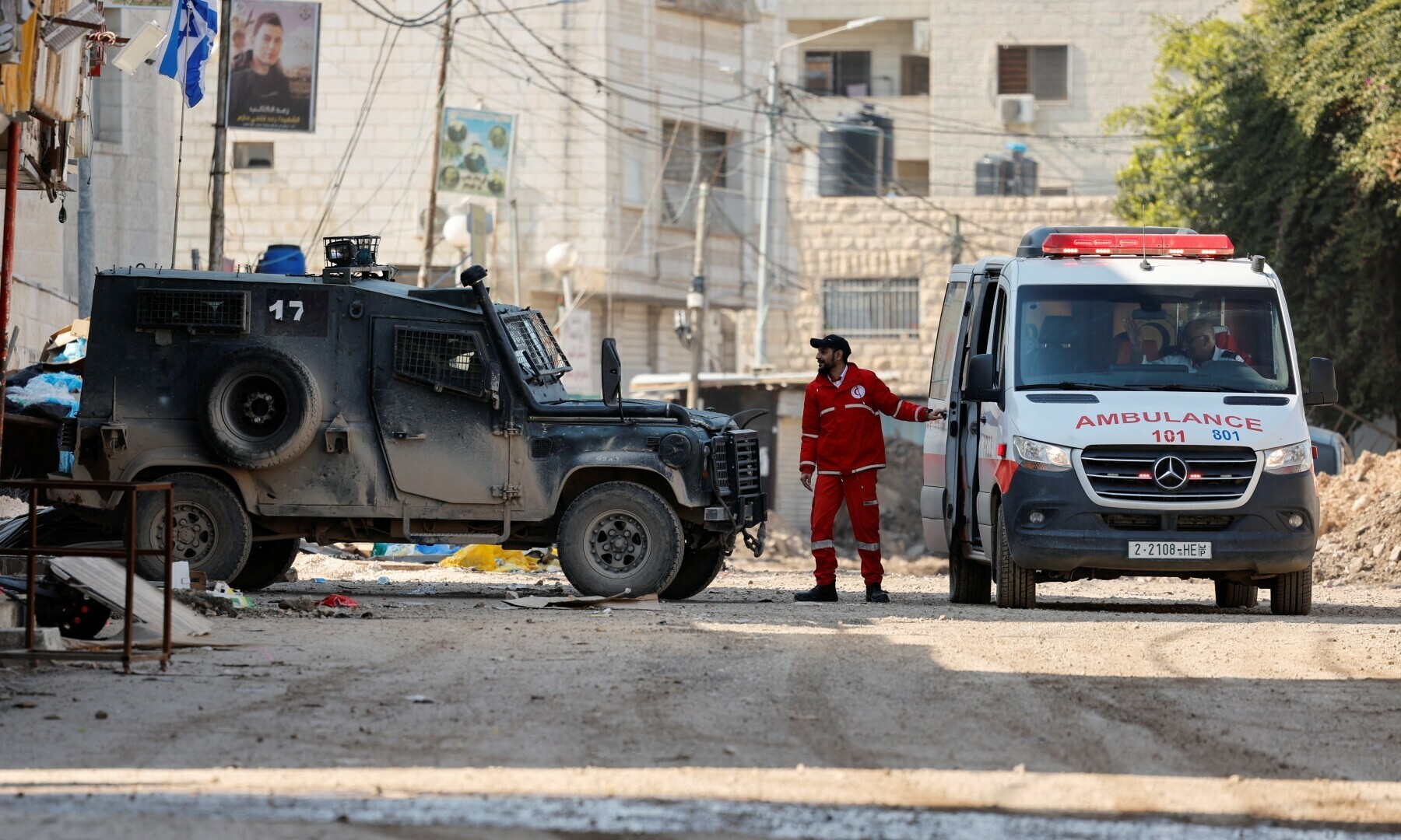 A man stands between an ambulance and an Israeli military vehicle, in Jenin, in the Israeli-occupied West Bank on January 29. &mdash; Reuters/Raneen Sawafta 