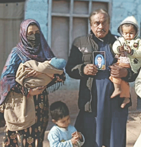 Mohammad Akbar Faiz holds the picture of his son Yasir, who had inadvertently crossed the LoC, in their home in Tetrinote area of Poonch on Sunday. The wife and three children of Yasir are with him. &mdash; Dawn