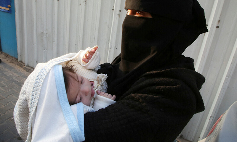 A Palestinian woman carries a sick child before leaving Gaza for treatment abroad through Rafah crossing, in Khan Younis in the southern Gaza Strip on February 1. &mdash; Reuters
