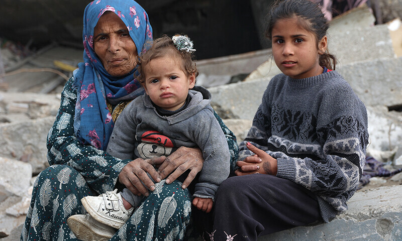 A Palestinian woman and children sit amid the rubble of destroyed buildings at Saftawi street in Jabalia, in the northern Gaza Strip, on February 5 during a ceasefire in the Israeli invasion of Gaza. &mdash; AFP