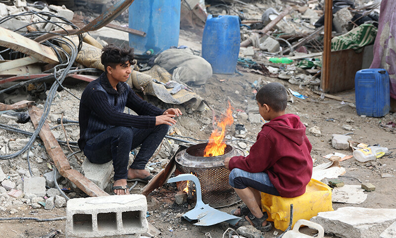 Palestinians warm themselves by a fire amid the rubble of destroyed buildings at Saftawi street in Jabalia, in the northern Gaza Strip, on February 5 during a ceasefire in the Israeli invasion of Gaza. &mdash; AFP